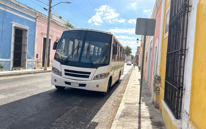 White city bus stopped on a street of pastel colonial buildings in Mérida's historic center