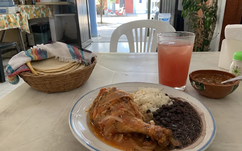 Plate of home-style lunch with rice, beans, stewed chicken and tortillas at a small Mérida eatery