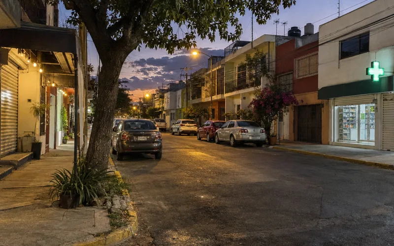 Residential neighborhood street in a Mexican city at dusk with streetlights coming on