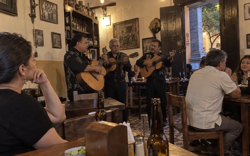 Trio of musicians playing guitars in a small cantina in Centro Mérida while customers sit at tables