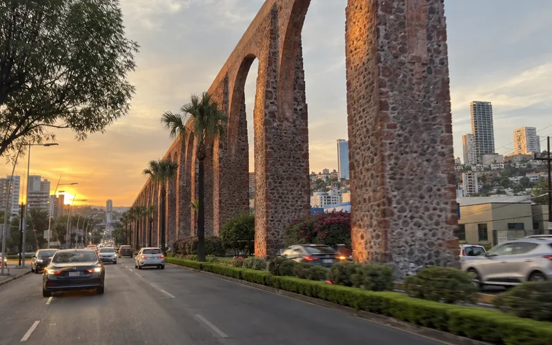 Stone arches of the Querétaro aqueduct beside a city avenue