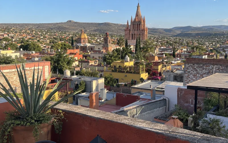 Rooftop view over San Miguel de Allende with the pink church spires and distant hills