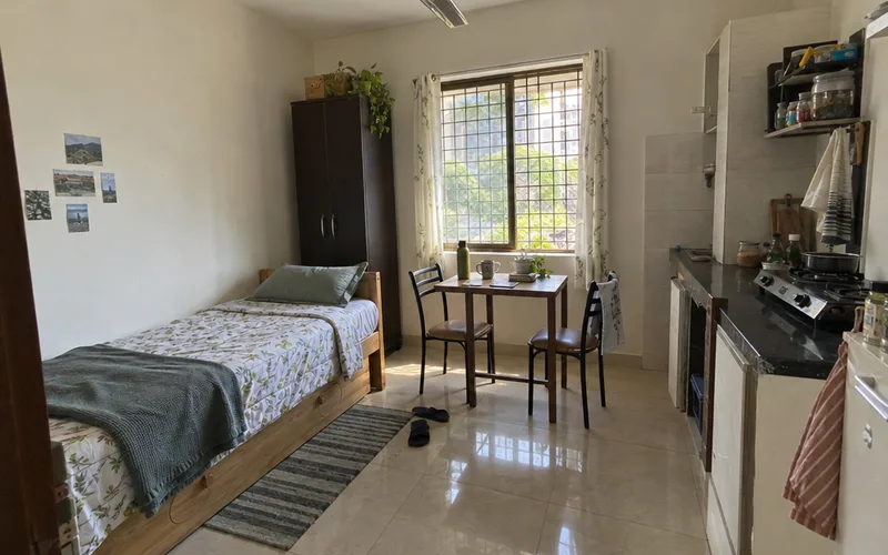 Small simple studio apartment with a bed, a ceiling fan and a two-burner stove
